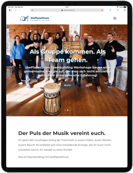The hero section for thePlanetDrum website. Displaying a group of people celebrating after a workshop 